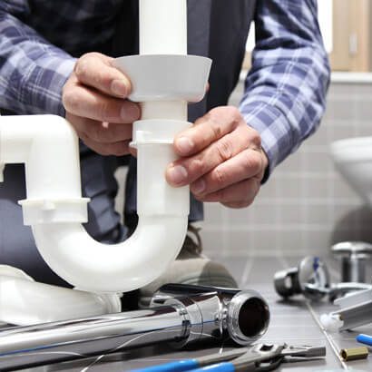 Installation d'un siphon sous un évier avec des outils de plomberie à proximité.
